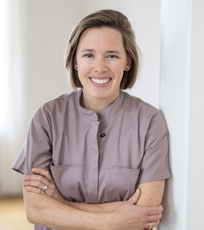 Frau Dr. Beckmann steht in einem Tührrahmen und lächelt in die Kamera