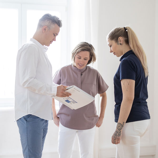 Frau Dr. Beckmann, Herr Dr. Beckmann und eine medizinische Fachangestellte besprechen sich